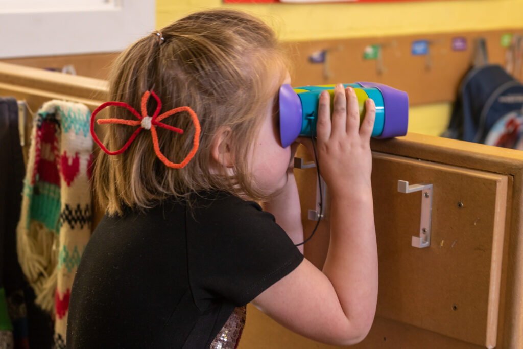 a girl trying to see something through her binoculars