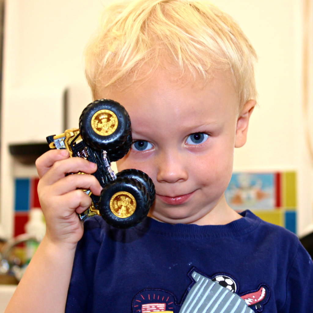 a blonde boy holding his car toy
