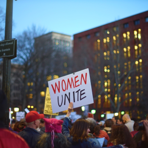 a sign: Women Unite