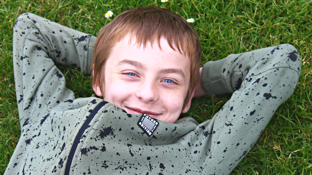 a boy laid down in the grass, relaxing